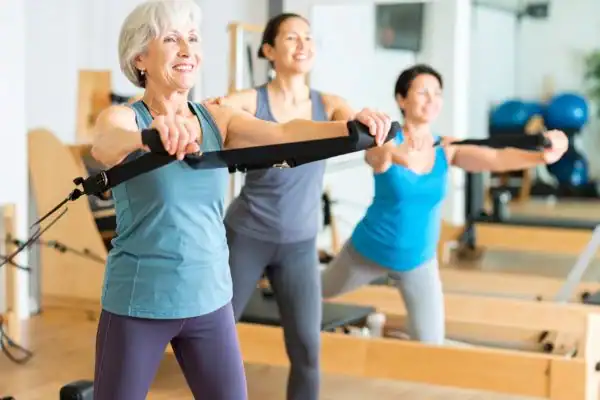 Toning Arms After 60: Empowering Womens Fitness Through Effective Weight Training 2 older woman doing weight training Twickenham and resistance in the gym to tone upper arms